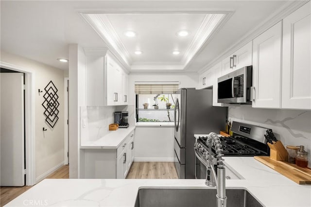 314 Molokai Dr, Placentia, CA 92870 - kitchen featuring appliances with stainless steel finishes, crown molding, a tray ceiling, white cabinets, and light wood-type flooring