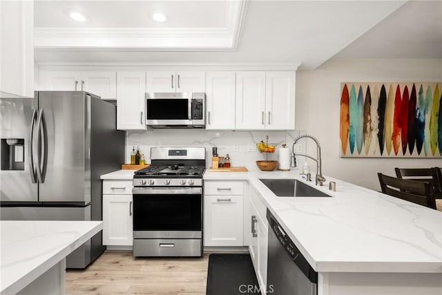 314 Molokai Dr, Placentia, CA 92870 - kitchen with appliances with stainless steel finishes, a peninsula, crown molding, white cabinetry, and light wood finished floors