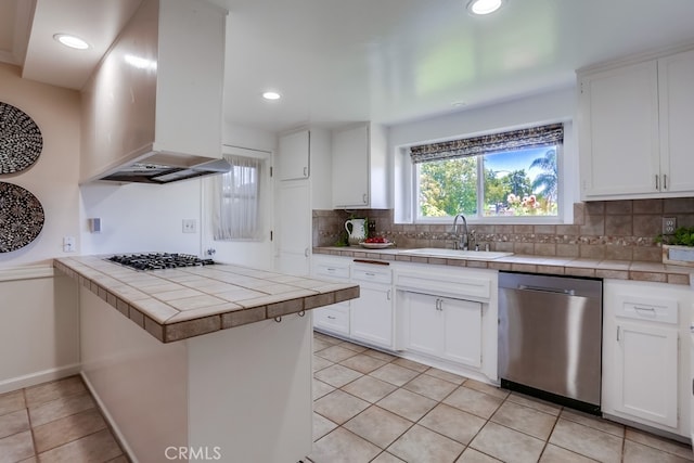 25001 Mackenzie St, Laguna Hills, CA 92653 - kitchen with stainless steel appliances, wall chimney range hood, tile counters, backsplash, and white cabinets