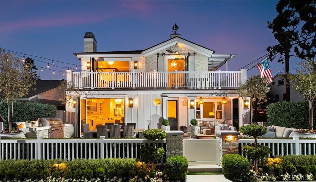 521 Poinsettia Ave, Corona Del Mar, CA 92625 - back of property with a balcony, a fenced front yard, a chimney, board and batten siding, and an outdoor hangout area