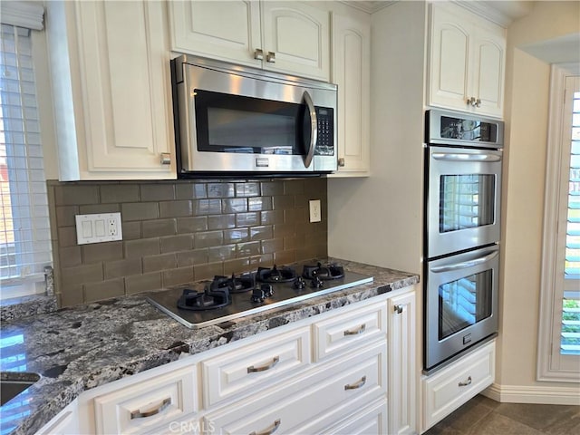 868 Ethelinda Way, Brea, CA 92821 - kitchen with appliances with stainless steel finishes, decorative backsplash, dark stone counters, dark tile patterned flooring, and white cabinets