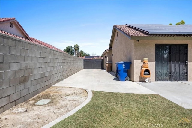 3105 Whisper Oak Way, Bakersfield, CA 93311 - view of side of home with stucco siding, roof mounted solar panels, a fenced backyard, a patio, and a tiled roof