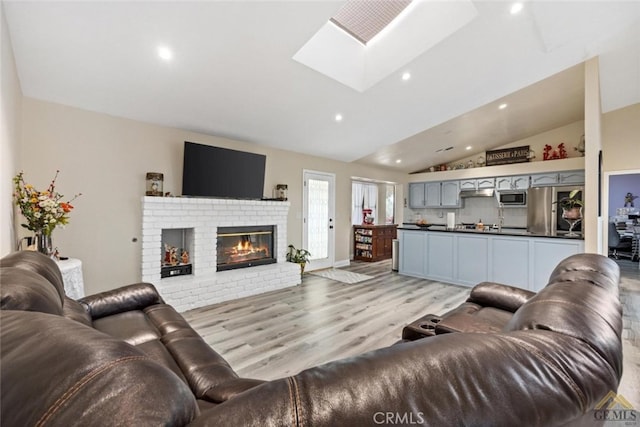 3105 Whisper Oak Way, Bakersfield, CA 93311 - living area featuring a skylight, vaulted ceiling, light wood-style flooring, recessed lighting, and a fireplace