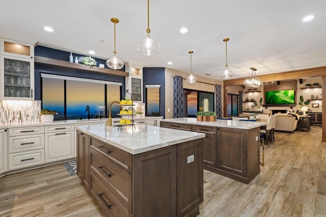 1966 Las Lomas, Vista, CA 92084 - kitchen featuring an island with sink, white cabinets, tasteful backsplash, light wood-style floors, and recessed lighting