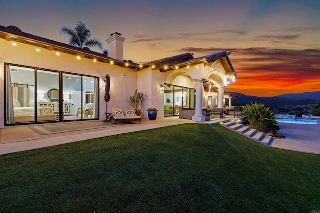1966 Las Lomas, Vista, CA 92084 - back of house at dusk featuring a patio area, a lawn, stucco siding, outdoor lounge area, and a chimney
