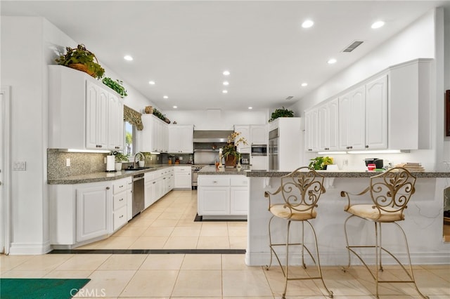 43110 Palomino Cir, Temecula, CA 92590 - kitchen with appliances with stainless steel finishes, light tile patterned floors, a peninsula, a breakfast bar area, and white cabinetry