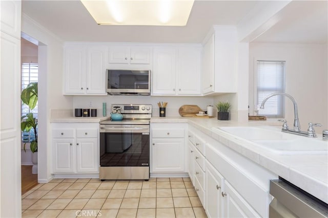 2217 E Brower St, Simi Valley, CA 93065 - kitchen with stainless steel appliances, white cabinetry, light tile patterned floors, and ornamental molding