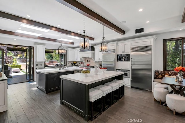 5329 Shirley Ave, Tarzana, CA 91356 - kitchen with appliances with stainless steel finishes, a center island, decorative backsplash, dark wood-style floors, and beam ceiling