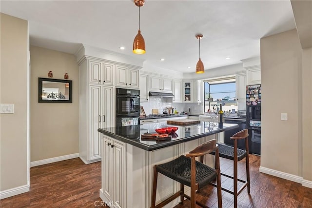 481 S Cedar Dr, Covina, CA 91723 - kitchen with black appliances, a kitchen breakfast bar, dark countertops, white cabinets, and dark wood-type flooring