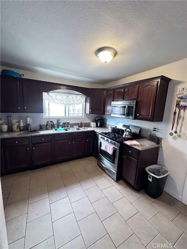 418 W 103rd St, Los Angeles, CA 90003 - kitchen with appliances with stainless steel finishes, a textured ceiling, dark brown cabinets, and light tile patterned floors