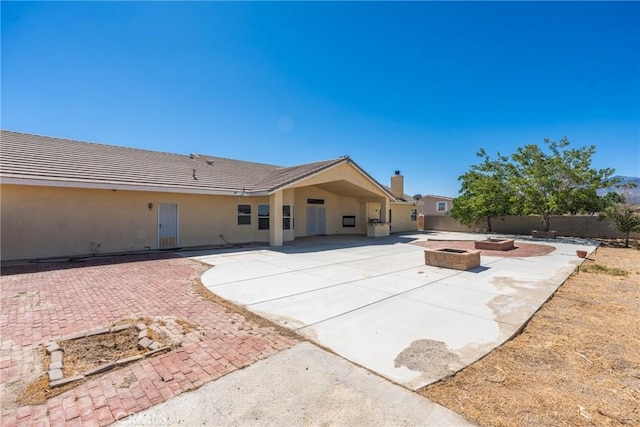13212 Primavera Rd, Pinon Hills, CA 92372 - back of property featuring an outdoor fire pit, a patio, a fenced backyard, stucco siding, and a chimney