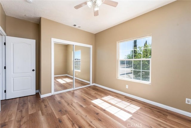 13212 Primavera Rd, Pinon Hills, CA 92372 - unfurnished bedroom featuring multiple windows, wood finished floors, a closet, and ceiling fan