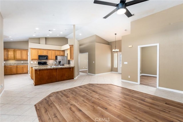 13212 Primavera Rd, Pinon Hills, CA 92372 - kitchen featuring black microwave, stainless steel refrigerator with ice dispenser, light tile patterned floors, open floor plan, and high vaulted ceiling
