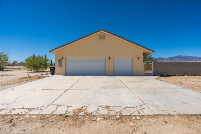13212 Primavera Rd, Pinon Hills, CA 92372 - view of home's exterior with stucco siding, a gate, a detached garage, and a mountain view