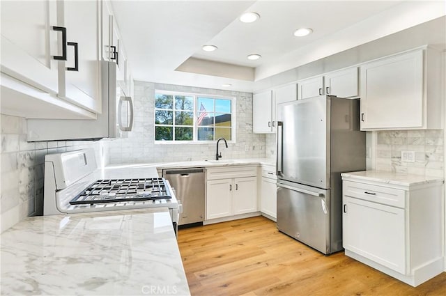 33621 Blue Lantern St, Dana Point, CA 92629 - kitchen featuring stainless steel appliances, light stone countertops, decorative backsplash, white cabinetry, and light wood-type flooring