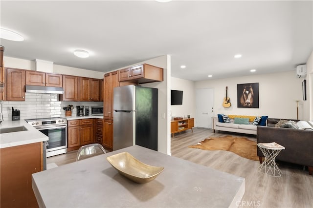 341 Carriage Dr Unit 51-A, Santa Ana, CA 92707 - kitchen featuring appliances with stainless steel finishes, under cabinet range hood, open floor plan, light wood-style floors, and brown cabinets