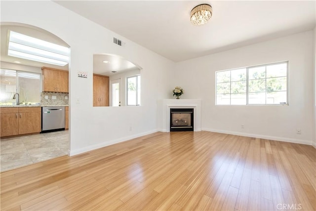 120 Rue Monet, Lake Forest, CA 92610 - unfurnished living room featuring a fireplace, light wood-style flooring, arched walkways, and a chandelier
