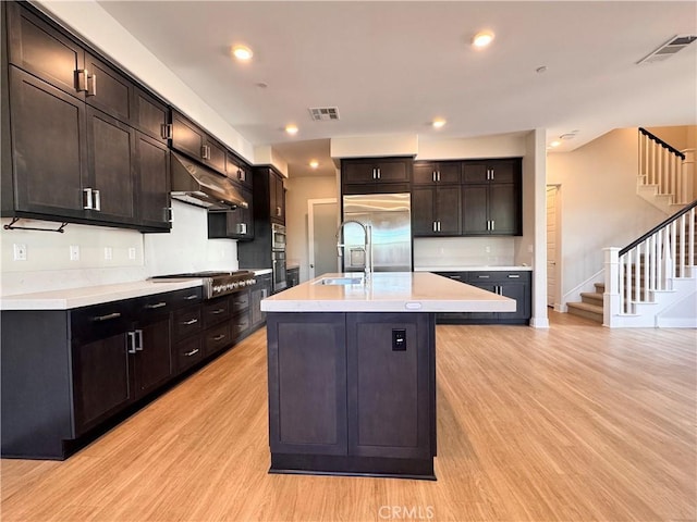 325 Sawbuck, Irvine, CA 92618 - kitchen with stainless steel appliances, under cabinet range hood, light wood-style flooring, light countertops, and an island with sink