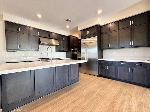 325 Sawbuck, Irvine, CA 92618 - kitchen featuring built in refrigerator, under cabinet range hood, light countertops, light wood-style floors, and recessed lighting