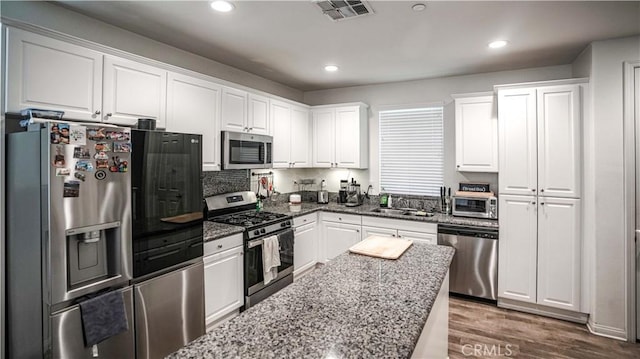 7600 Channel View St, Chino, CA 91708 - kitchen featuring appliances with stainless steel finishes, white cabinets, dark stone countertops, dark wood-type flooring, and recessed lighting