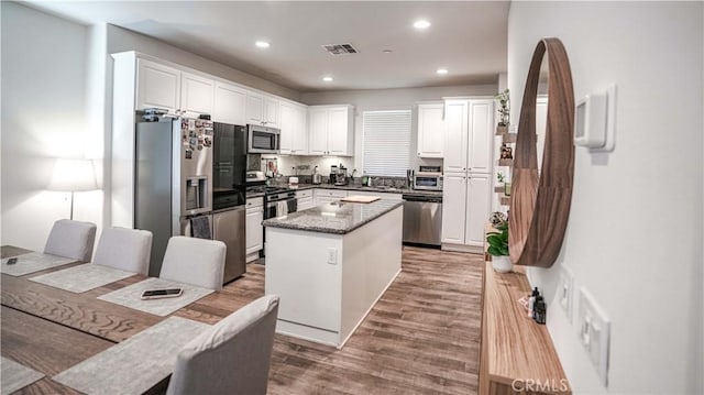 7600 Channel View St, Chino, CA 91708 - kitchen featuring stainless steel appliances, white cabinets, a kitchen island, wood finished floors, and recessed lighting