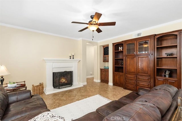 32974 Anasazi Dr, Temecula, CA 92592 - living area with ceiling fan, ornamental molding, a warm lit fireplace, arched walkways, and light tile patterned floors
