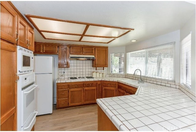 6318 Westview Dr, Riverside, CA 92506 - kitchen featuring white appliances, brown cabinetry, light wood-type flooring, under cabinet range hood, and tasteful backsplash