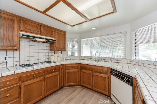 6318 Westview Dr, Riverside, CA 92506 - kitchen featuring white appliances, under cabinet range hood, light wood-type flooring, brown cabinetry, and tasteful backsplash
