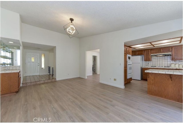 6318 Westview Dr, Riverside, CA 92506 - kitchen featuring tile counters, under cabinet range hood, brown cabinetry, and white appliances