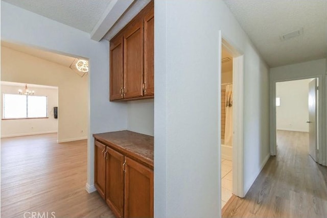 6318 Westview Dr, Riverside, CA 92506 - corridor with light wood-style floors, a chandelier, and a textured ceiling