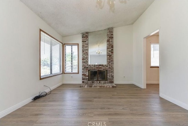 6318 Westview Dr, Riverside, CA 92506 - unfurnished living room featuring vaulted ceiling, wood finished floors, a fireplace, and a textured ceiling