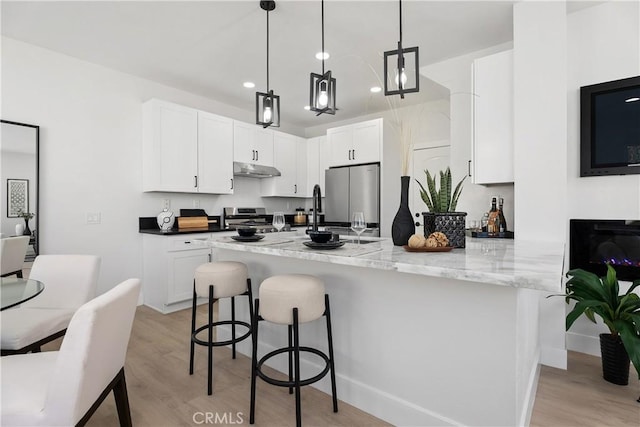 14941 Almond Grove Ct, Tustin, CA 92780 - kitchen featuring stainless steel appliances, a breakfast bar area, under cabinet range hood, light wood-style flooring, and recessed lighting