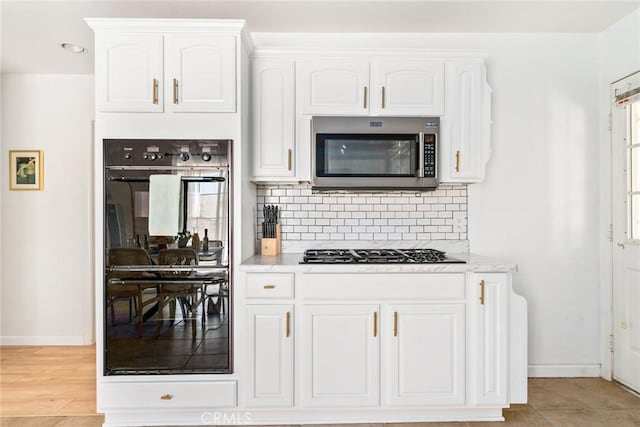 7787 Deer Trl, Yucca Valley, CA 92284 - kitchen with appliances with stainless steel finishes, backsplash, white cabinets, and light wood-style flooring