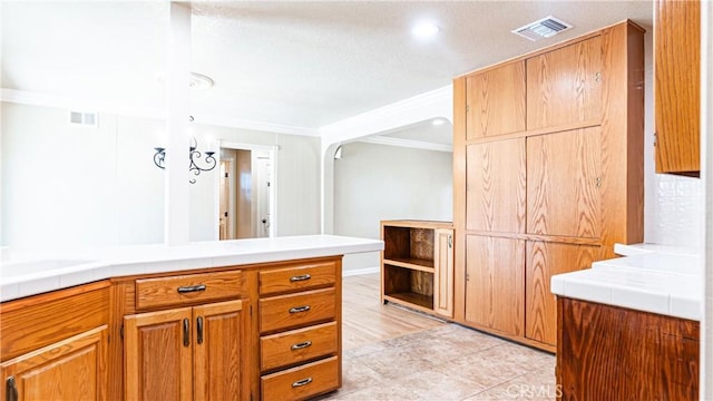 5449 E Fairbrook St, Long Beach, CA 90815 - kitchen featuring crown molding, tile counters, brown cabinets, arched walkways, and recessed lighting