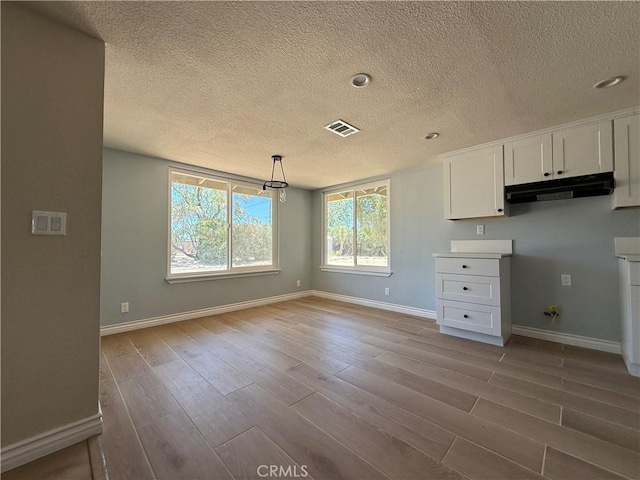 20219 Osseo Rd, Apple Valley, CA 92308 - kitchen featuring under cabinet range hood, a textured ceiling, wood finished floors, white cabinets, and pendant lighting