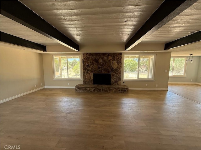 20219 Osseo Rd, Apple Valley, CA 92308 - unfurnished living room with a stone fireplace, wood finished floors, and a wooden ceiling with exposed beams