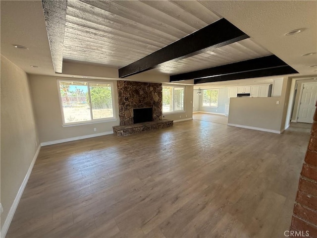 20219 Osseo Rd, Apple Valley, CA 92308 - unfurnished living room featuring a stone fireplace, wood finished floors, and beam ceiling