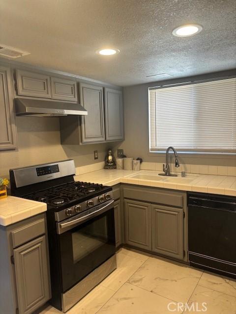 1725 Le Niche Ln, Lancaster, CA 93535 - kitchen with gas stove, under cabinet range hood, black dishwasher, gray cabinets, and recessed lighting