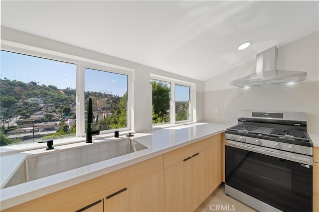 4365 Oneill St, Los Angeles, CA 90032 - kitchen with stainless steel gas stove, wall chimney exhaust hood, light brown cabinetry, vaulted ceiling, and light countertops