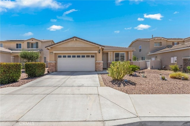 16767 Desert Lily St, Victorville, CA 92394 - view of front of home featuring an attached garage, concrete driveway, stucco siding, and stone siding
