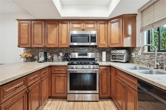 301 W Loraine St Unit 3, Glendale, CA 91202 - kitchen featuring stainless steel appliances, brown cabinets, light stone countertops, backsplash, and light wood finished floors