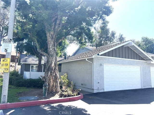 25511 Polaris Ln, Lake Forest, CA 92630 - view of front of home with an attached garage, asphalt driveway, stucco siding, and board and batten siding