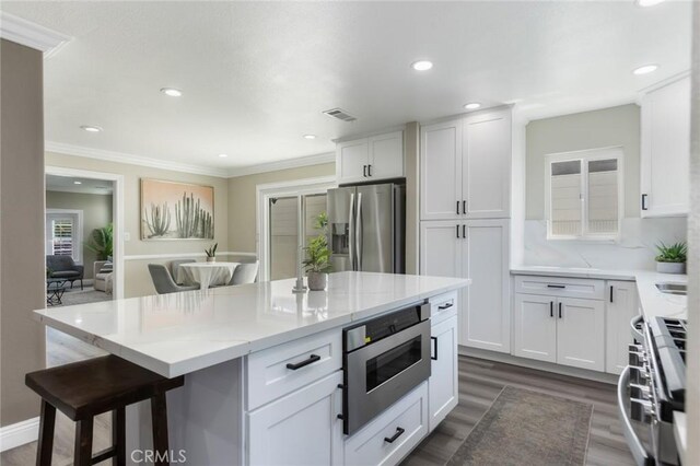 2306 255th St, Lomita, CA 90717 - kitchen with stainless steel appliances, a breakfast bar area, white cabinetry, light stone countertops, and dark wood-type flooring