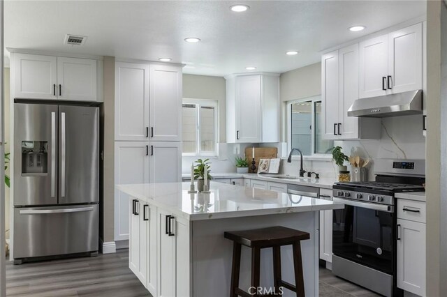 2306 255th St, Lomita, CA 90717 - kitchen with appliances with stainless steel finishes, under cabinet range hood, white cabinets, a center island, and recessed lighting