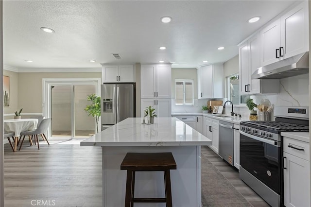 2306 255th St, Lomita, CA 90717 - kitchen featuring stainless steel appliances, under cabinet range hood, a center island, a breakfast bar, and white cabinets