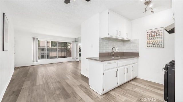 4431 Don Ricardo Dr Unit 20, Los Angeles, CA 90008 - kitchen with light wood-type flooring, wall chimney exhaust hood, white cabinetry, backsplash, and gas range oven