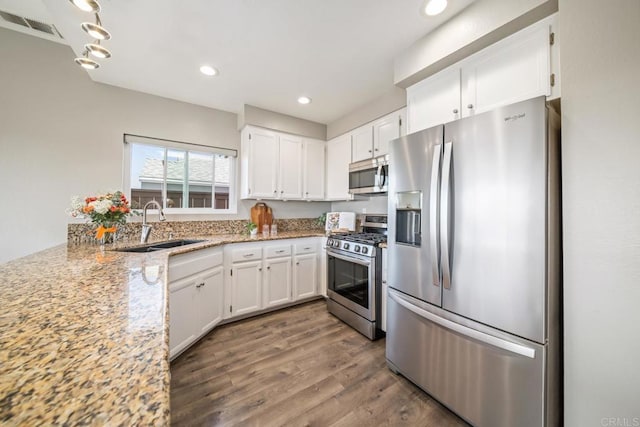 4507 Carnaby Ct, Carlsbad, CA 92010 - kitchen with stainless steel appliances, white cabinetry, dark wood finished floors, light stone countertops, and recessed lighting