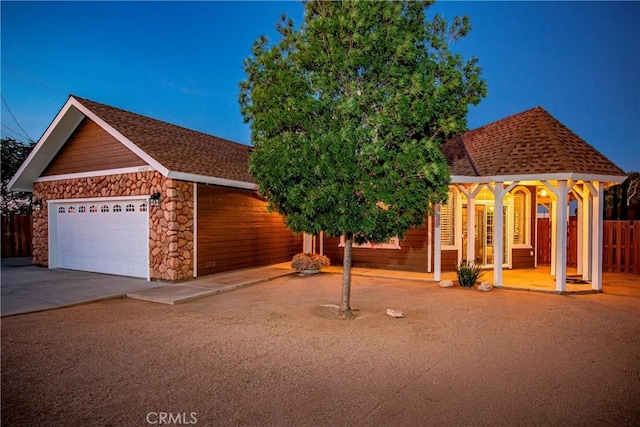 33430 133rd St E, Pearblossom, CA 93553 - view of front of house featuring stone siding, a garage, and roof with shingles