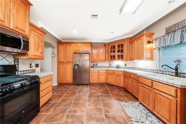 33430 133rd St E, Pearblossom, CA 93553 - kitchen with appliances with stainless steel finishes, ornamental molding, glass insert cabinets, tile counters, and decorative backsplash
