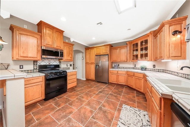 33430 133rd St E, Pearblossom, CA 93553 - kitchen with stainless steel appliances, glass insert cabinets, arched walkways, tile counters, and crown molding
